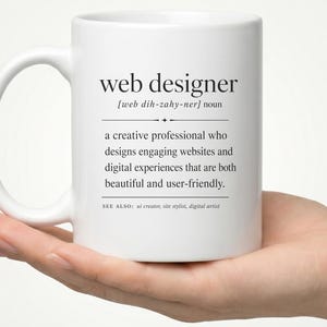 May include: A white ceramic mug featuring black printed text that defines the term web designer as a creative professional who designs engaging websites and digital experiences that are both beautiful and user-friendly, including phonetic pronunciation.