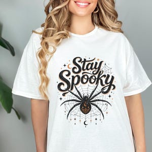 White t-shirt with "Stay Spooky" text and a large spider on a web.
