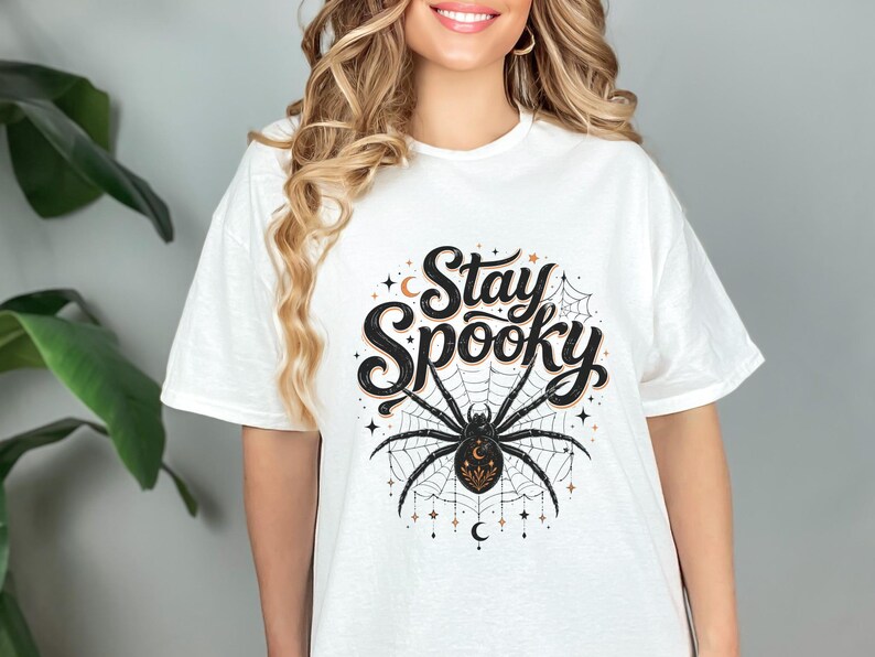 White t-shirt with "Stay Spooky" text and a large spider on a web.