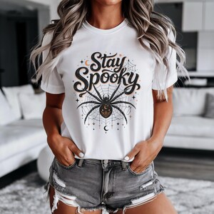 White t-shirt with black and orange spider graphic and "Stay Spooky" text.