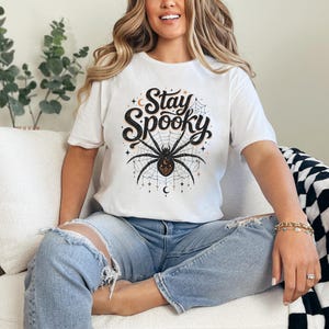 White t-shirt with "Stay Spooky" text and a spiderweb graphic.
