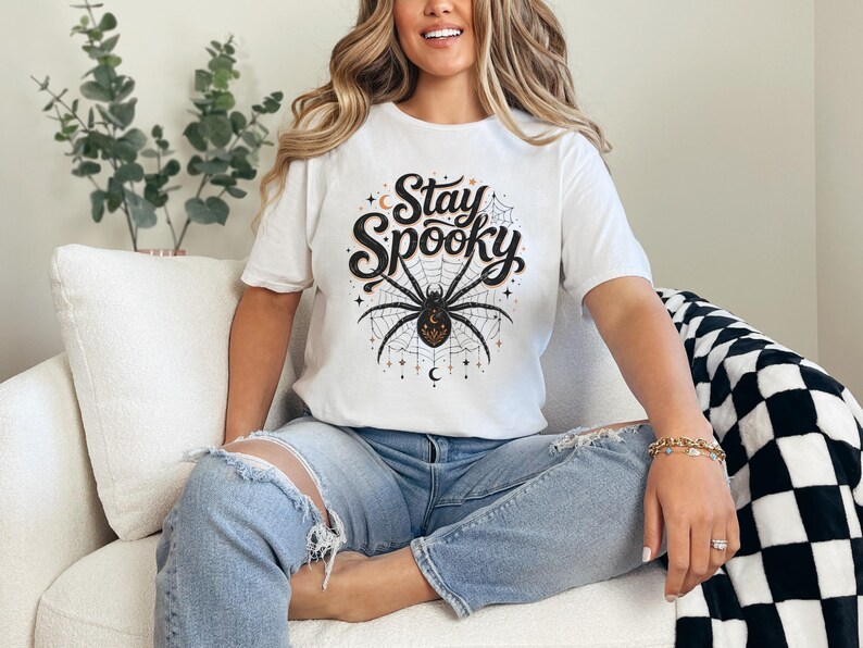 White t-shirt with "Stay Spooky" text and a spiderweb graphic.