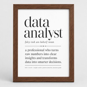 Pode incluir: Uma impressão de parede emoldurada com a definição de dicionário do substantivo data analyst. O texto diz: data analyst [dey-tuh an-luhst] noun, a professional who turns raw numbers into clear insights and transforms data into smarter decisions. SEE ALSO: insight seeker, pattern detective, decision guide. A impressão está dentro de uma moldura de madeira castanho-escura.