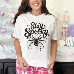 White t-shirt with "Stay Spooky" text and a large spider graphic.