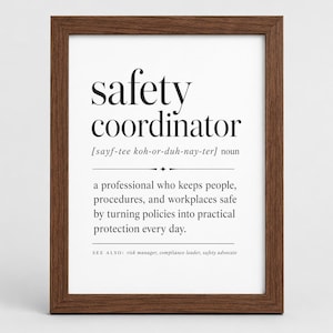May include: A framed wall print featuring the dictionary-style definition of a safety coordinator. The text reads: safety coordinator [sayf-tee koh-or-duh-nay-ter] noun, a professional who keeps people, procedures, and workplaces safe.