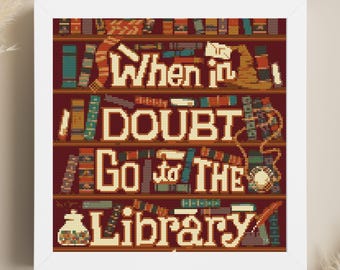 Op de afbeelding: Een kruissteekpatroon met een boekenkast vol boeken en de tekst "When in doubt, go to the library".