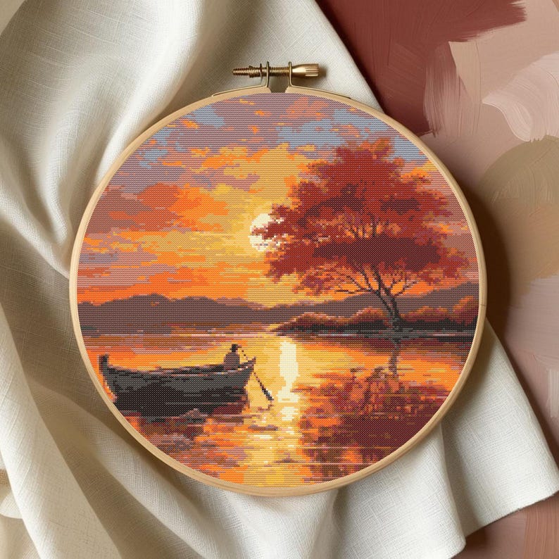 K&ouml;nnte beinhalten: Eine Kreuzstich-Stickerei, die eine Sonnenuntergangsszene mit einer einsamen Figur in einem Boot auf einem See zeigt. Der Himmel ist in leuchtenden Orange- und Rosat&ouml;nen gehalten, mit einem gro&szlig;en Baum am Ufer.