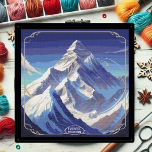 May include: A cross-stitch pattern of Mount Everest, a snow-capped mountain range with a blue sky and white clouds. The text "EVEREST MOUNTAIN" is at the bottom of the image.