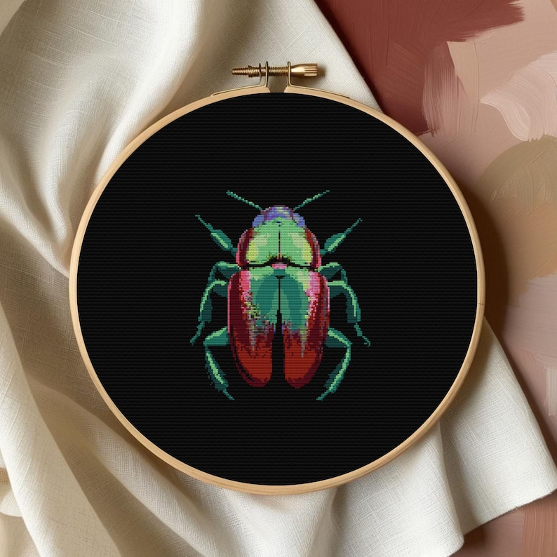 May include: A close-up of a cross-stitch embroidery hoop with a black background and a colorful beetle design. The beetle is red, green, and black with a metallic sheen.