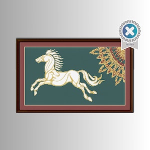 May include: A framed cross-stitch artwork featuring a white horse in mid-gallop against a teal background. The horse is detailed with a flowing mane and tail. A decorative sunburst design is in the upper right corner. The frame is a dark reddish-brown.