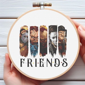 May include: Cross-stitch embroidery in a wooden hoop featuring five horror movie characters. The word "FRIENDS" is stitched below the characters. The characters include Jason Voorhees, Chucky, and Freddy Krueger.