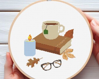 May include: A white ceramic mug with a tea bag, a brown book, a blue candle, and a pair of glasses on a white background.