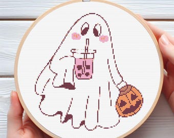 Puede incluir: Bordado de punto de cruz en un aro de madera que representa un fantasma amigable con té de burbujas y una calabaza. El fantasma tiene mejillas rosadas y sonríe. El diseño está bordado sobre tela blanca.