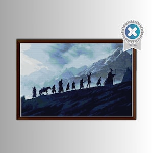 May include: A framed cross-stitch depicting a silhouette of figures walking up a mountain, with a horse in the middle. The background shows a cloudy sky and mountains. The frame is brown, and a "TESTED" seal is in the upper right corner.