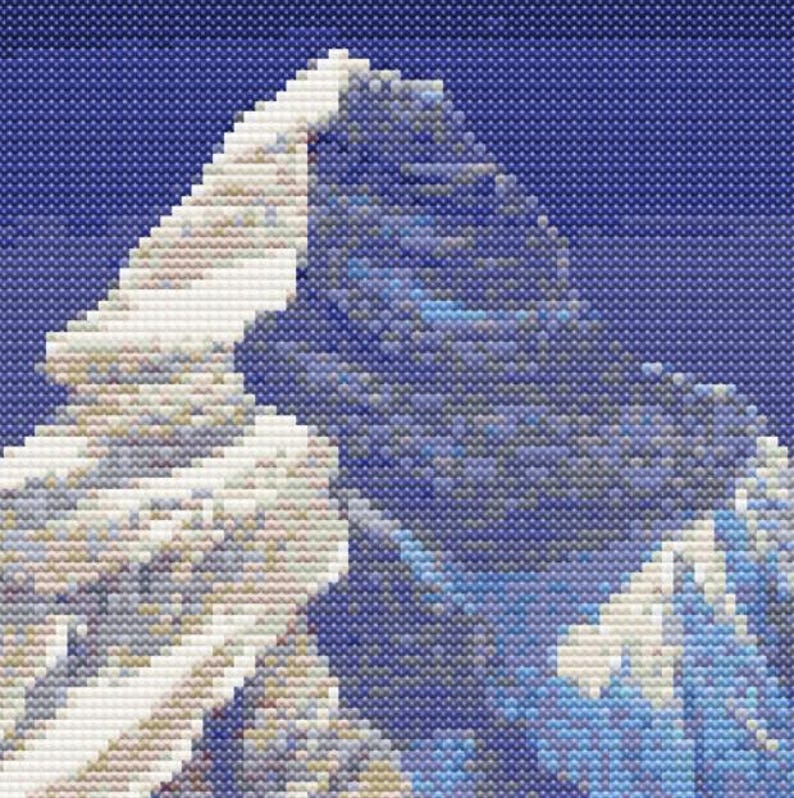 May include: A close-up of a snow-capped mountain peak against a blue sky. The mountain is made up of white and gray rock, with a hint of blue in the shadows. The sky is a deep blue, with no clouds visible.