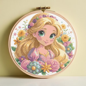 May include: A cross-stitch embroidery of a cartoon princess with long blonde hair, green eyes, and a floral crown. The princess is surrounded by colorful flowers in shades of pink, yellow, and blue. The embroidery is set in a round wooden hoop.