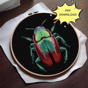 May include: A cross-stitch embroidery hoop with a colorful beetle design. The beetle is green, red, and black with a detailed design. The background is black.