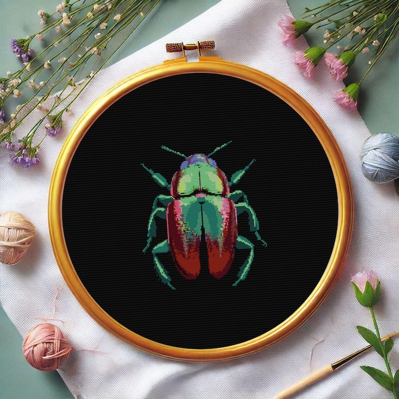 May include: A cross-stitch embroidery hoop with a black fabric background featuring a colorful beetle with green, red, and iridescent wings.