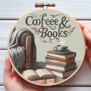 May include: A round embroidery hoop featuring a beige background with the text "Coffee & Books" in brown lettering. The design showcases a cosy scene with a pile of books, a cup of coffee, and a blanket draped over a chair.