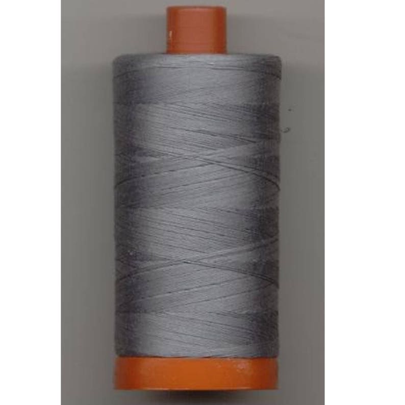May include: A spool of silver gray thread with an orange plastic bobbin.