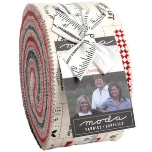 May include: A roll of fabric with a white background and red, black, and gray stripes. The fabric is wrapped around a cardboard tube. A white ribbon is tied around the fabric roll. A white tag with black text reads "moda fabrics + supplies".