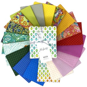 May include: A set of 20 fabric squares in various colors and patterns, including green, blue, yellow, red, and pink. The fabric squares are arranged in a fan shape and feature a variety of designs, such as polka dots, stripes, and floral prints. The fabric squares are packaged together with a white ribbon and a tag that reads "Free Spirit".
