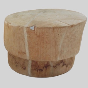 May include: A light brown, wooden stool with a round top and a slightly smaller base. The wood grain is visible, and the stool has a natural, rustic appearance. The stool is approximately 18 inches tall.
