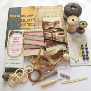 May include: A collection of vintage sewing supplies, including spools of thread, bias tape, ribbon, buttons, and sewing machine instructions. The color palette includes shades of brown, beige, and cream, with a touch of red. The text on the items is visible.