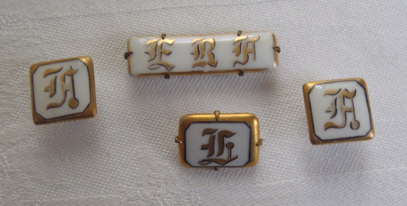 May include: Four white porcelain buttons with gold trim and black lettering. The buttons feature the letters "F", "R", and "H" in a stylized font.