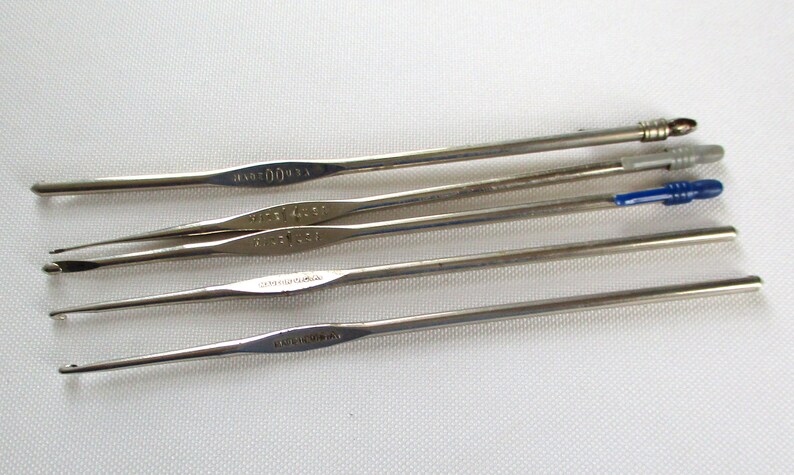 May include: A set of six silver crochet hooks of varying sizes. The hooks are arranged in a row, with the largest hook at the top and the smallest hook at the bottom.