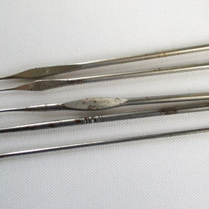 May include: A set of five silver crochet hooks of varying sizes. The hooks are made of metal and have a smooth, polished finish.