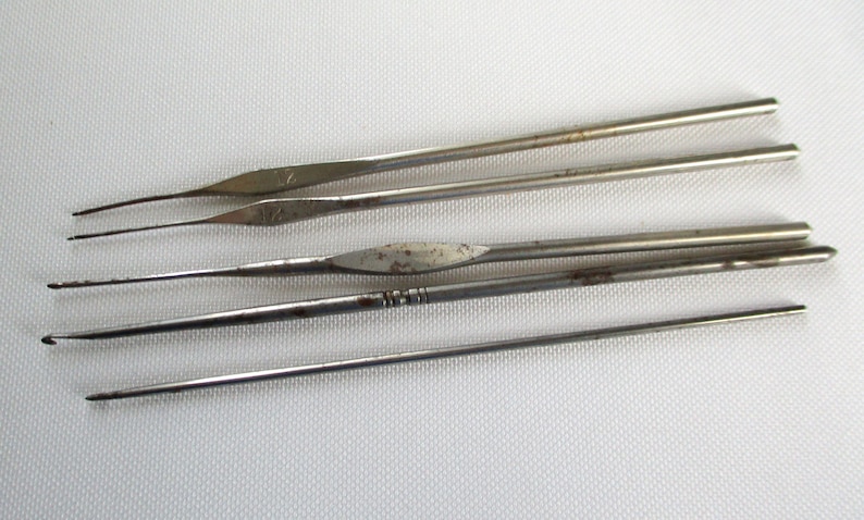 May include: A set of five silver crochet hooks of varying sizes. The hooks are made of metal and have a smooth, polished finish.