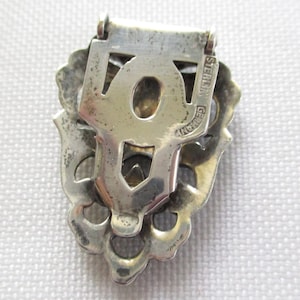 Puede incluir: Un broche de filigrana de plata con un cierre en la parte posterior. La parte posterior del broche est&aacute; marcada con "STERLING GERMANY".