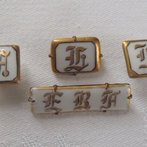 May include: Four gold-toned porcelain buttons with white enamel and gold lettering. The buttons feature the letters "F", "R", and "H" in a stylized font.