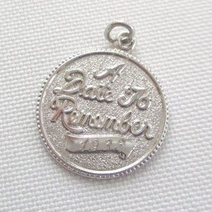 May include: A round silver-toned metal charm featuring a textured background and a beaded border. The charm is embossed with the script text A Date To Remember and a banner at the bottom containing the year 1988. It includes a small jump ring.