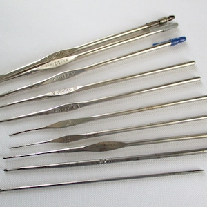 May include: A set of ten silver crochet hooks of varying sizes. The hooks are arranged in a row from largest to smallest. The hooks are labeled with their size in millimeters.