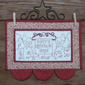 Peut inclure: Une tenture murale en tissu blanc avec une bordure rouge et un bas festonné. Le tissu présente un motif brodé de deux oiseaux avec une pancarte qui dit "merry christmas days".