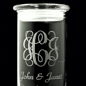 May include: A clear glass jar with an etched monogram and the text "John & Janet December 31, 1994".