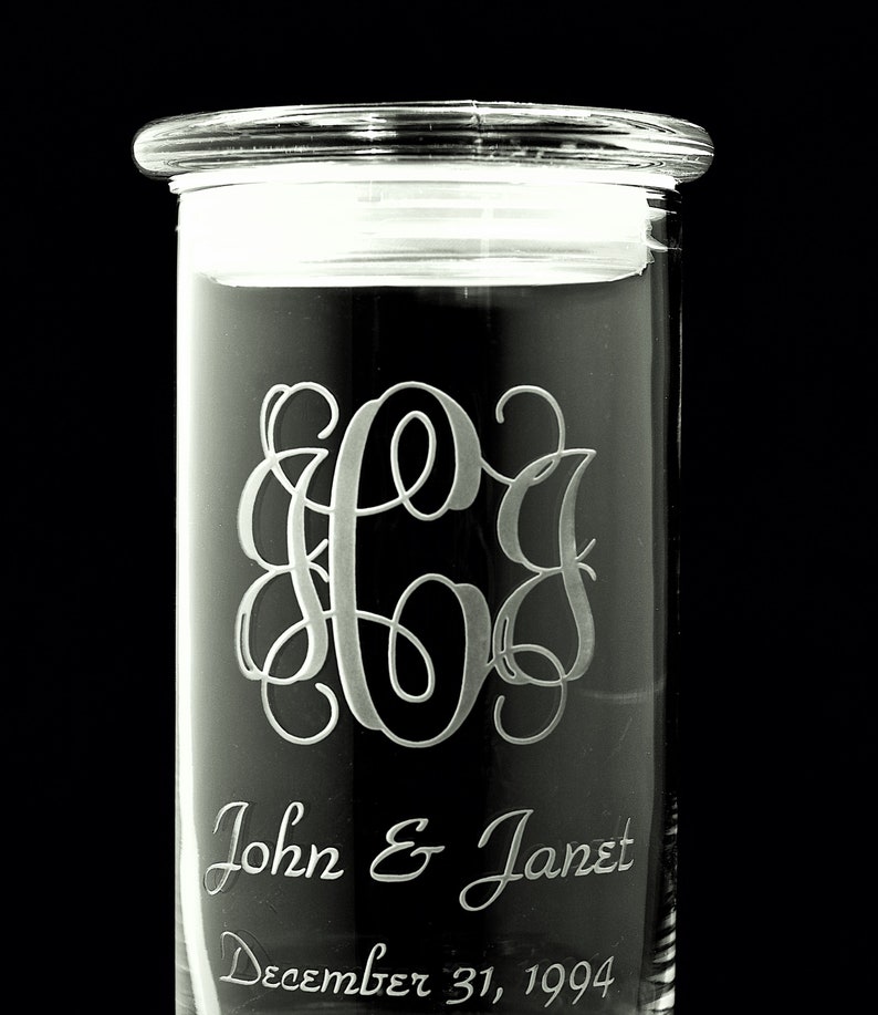 May include: A clear glass jar with an etched monogram and the text "John & Janet December 31, 1994".