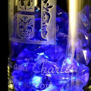 May include: A clear glass with blue glass beads inside. The glass is etched with the text "Lisa and Charles" and the date "Jul 30, 2016".