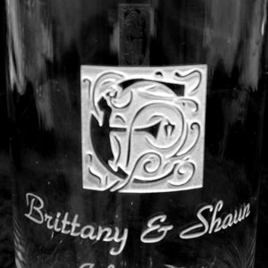 May include: A clear glass vase with an etched design of a letter "C" surrounded by floral motifs. The vase is engraved with the text "Brittany & Shawn".