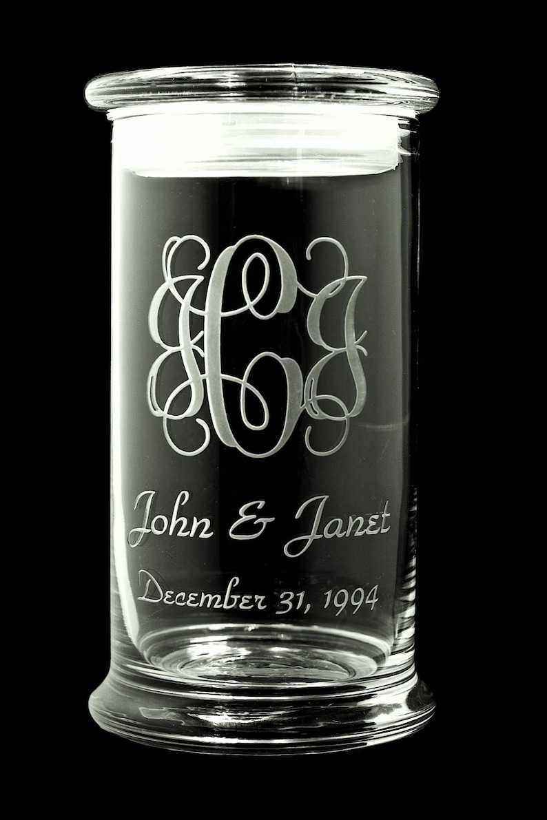 May include: A clear glass jar with a lid, engraved with the monogram "JGJ", the names "John & Janet", and the date "December 31, 1994".