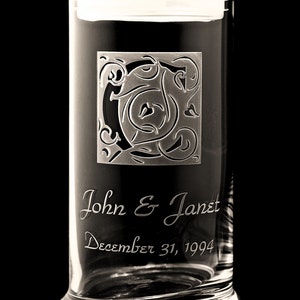 May include: A clear glass jar with a lid, engraved with a decorative initial and the text "John & Janet December 31, 1994".