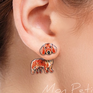 Op de afbeelding: Een paar oorbelhangers met een rode en bruine teckel. De kop van de hond zit op het bovenste deel van de oorbel en het lichaam hangt eronder.