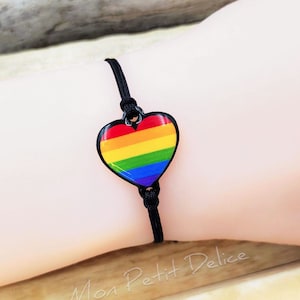 Puede incluir: Un brazalete de cuerda negro con un dije de corazón arcoíris. El dije está hecho de esmalte y tiene un acabado brillante.