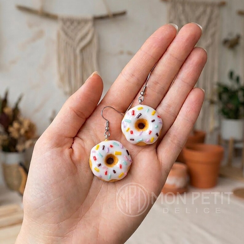 White sprinkle donut earrings held in hand to show actual scale and miniature size.