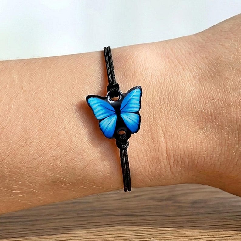 Blue butterfly bracelet handmade from shrink plastic and 3D glossy resin. Adjustable black cord with silver stainless steel beads for adults and kids. Perfect birthday gift for nature lovers.