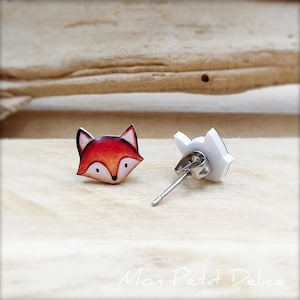 K&ouml;nnte beinhalten: Ein Paar Fuchs-Ohrstecker. Der Fuchs ist orange und wei&szlig; mit schwarzen Augen und einer schwarzen Nase. Die Ohrringe sind aus Polymer Clay gefertigt und haben silberne Ohrstecker.