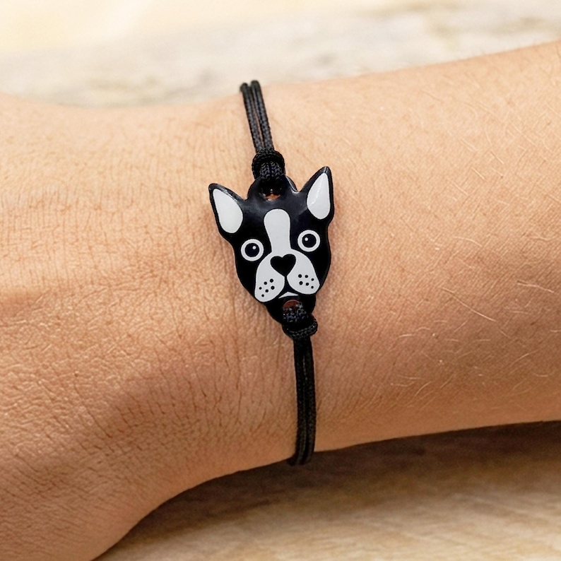 Handmade Boston Terrier bracelet worn on a wrist, featuring a black and white dog charm and adjustable black cord. Perfect dog mom gift idea.