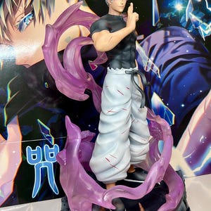 May include: A white and grey anime figurine with white hair and a black shirt. The figurine is standing on a rocky base with purple and pink translucent flames. The figurine is holding its right hand up in a fist.